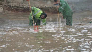 عاملا وطن يقومان بتصريف مياه في أحد شوارع عمان- (الغد)